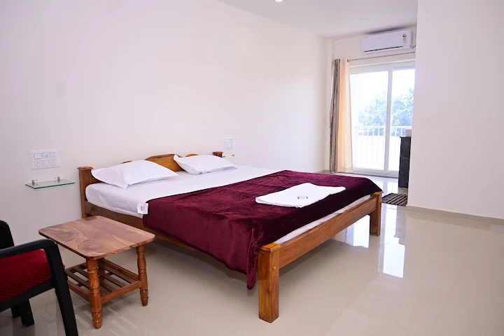 A guest room at Shri Arya Home Stay with an AC unit, wooden bed and balcony access